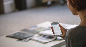 Frau benutzt sonnen App auf ihrem Handy um ihren Strom Verbrauch  zu ermitteln und somit Geld zu sparen 